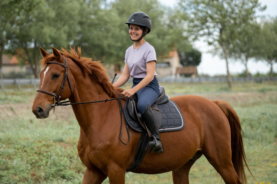 A person riding a chestnut horse outdoors