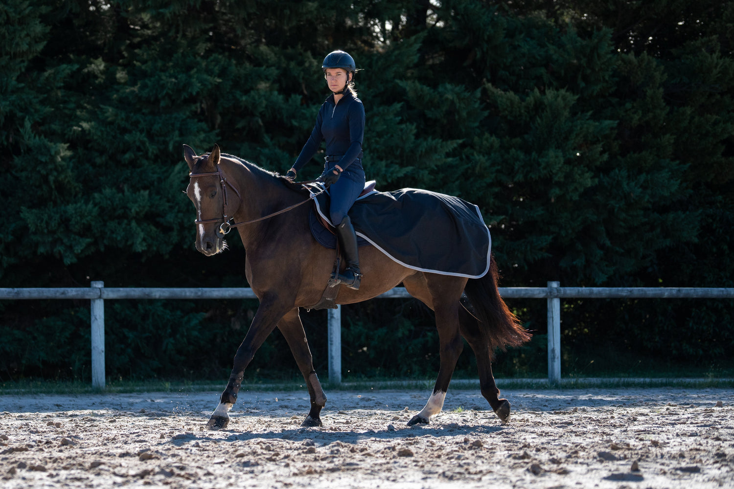 Rider on a horse wearing a black exercise rug