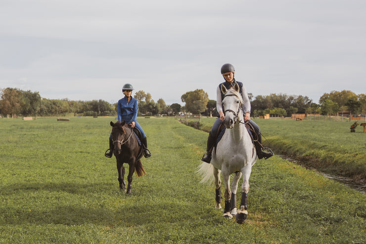 Two riders on horses in a grassy field